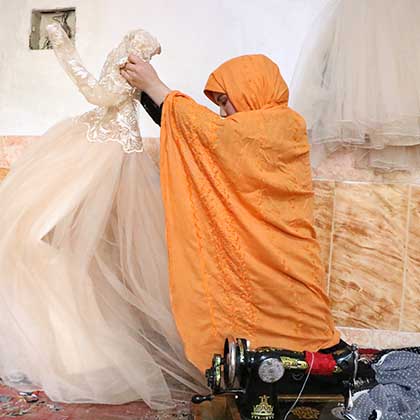 Photo of Somaya unfurling a wedding dress she had sewn.