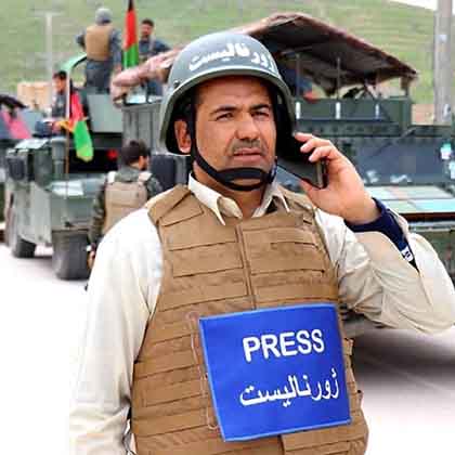 Qutbuddin Kohi fields a phone call near a passing military convoy outside Maimana, Faryab province, in early 2021.