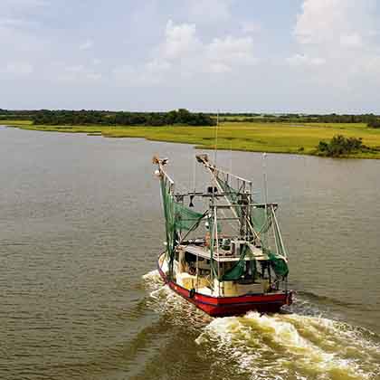 Aerial photograph of a shrimp boat sailing downstream.