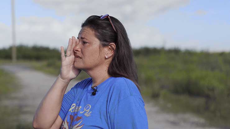 Photograph of a woman standing outside, wiping away a tear.